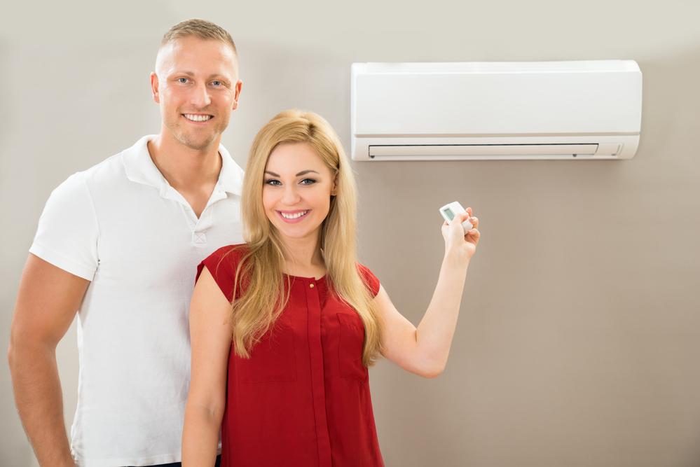 man and woman turning on AC unit