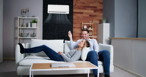 couple laying on couch under A/C
