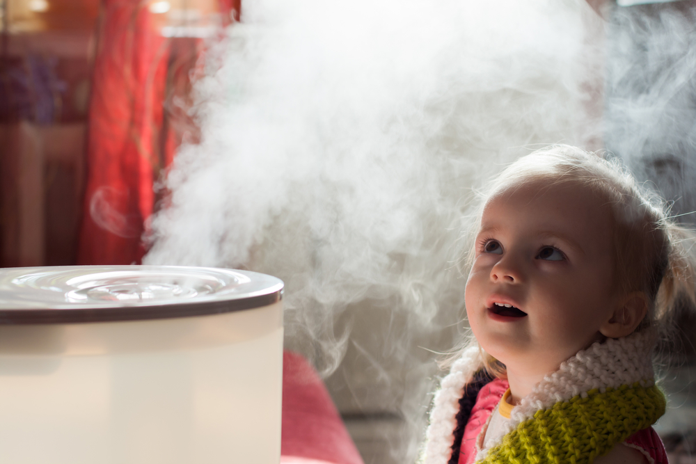 little girl staring at mist from humidifier